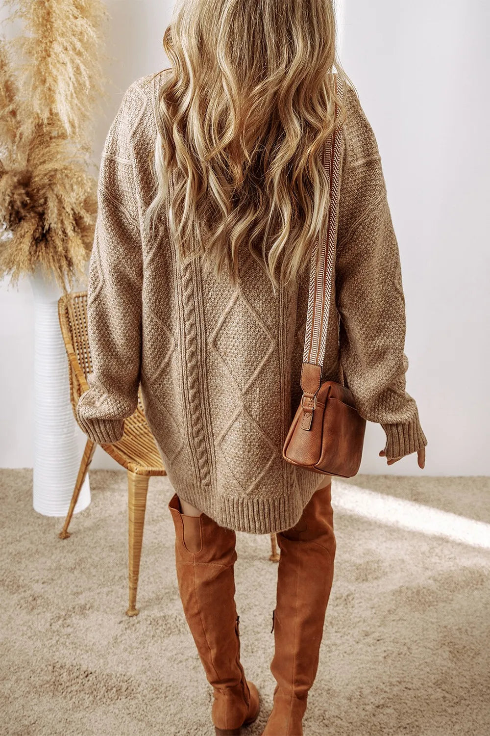 Taupe cable-knit sweater dress with diamond and rope patterns, oversized fit, dropped shoulders, and long sleeves.