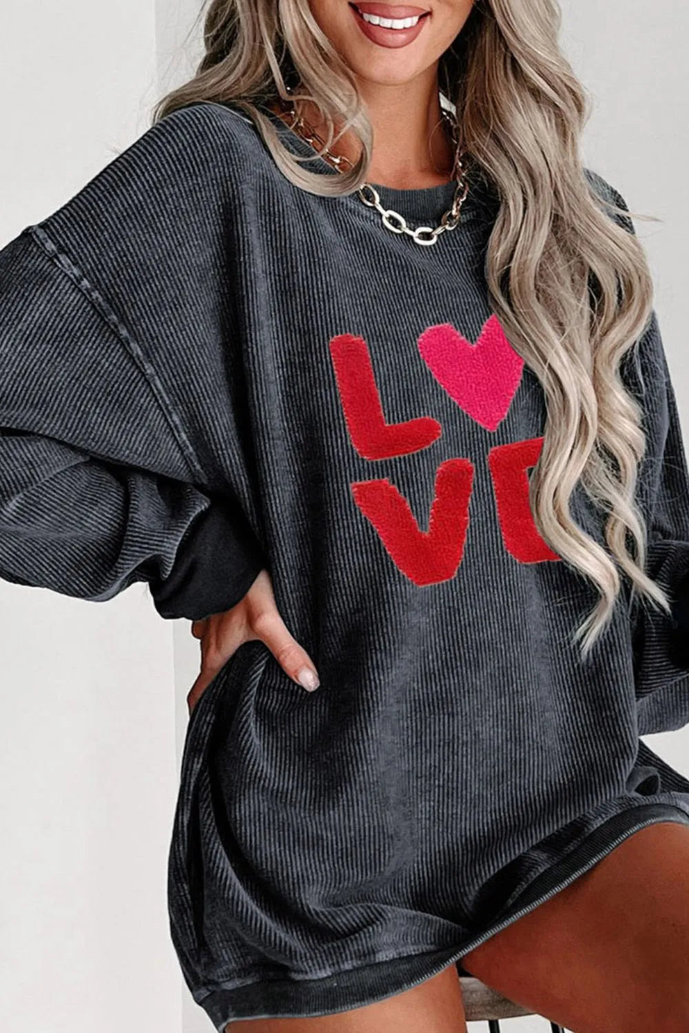 Black long sleeve sweatshirt with red LOVE text and pink heart on front, relaxed fit.