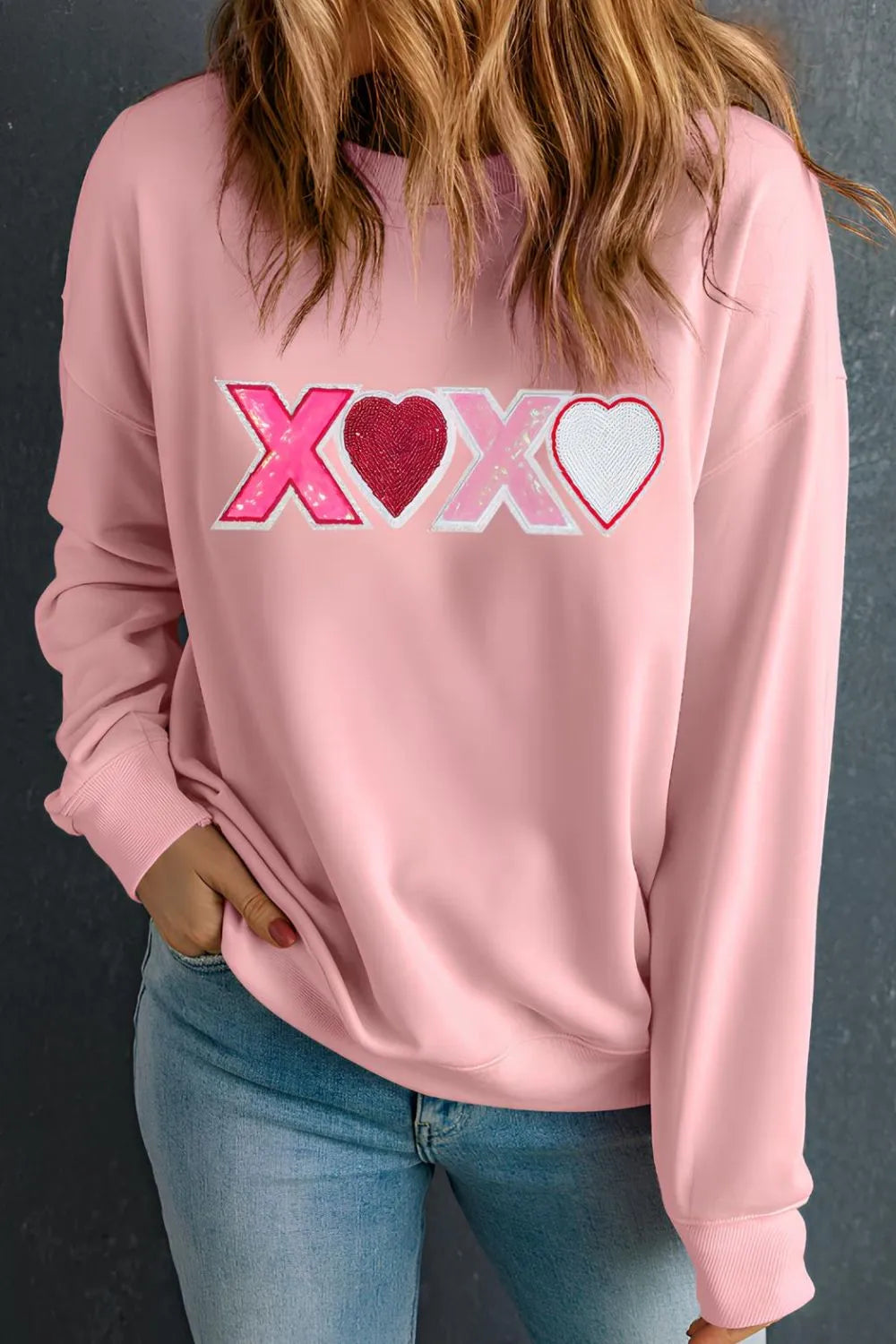 Dusty pink long sleeve sweatshirt with XOXO and heart graphic on the front.