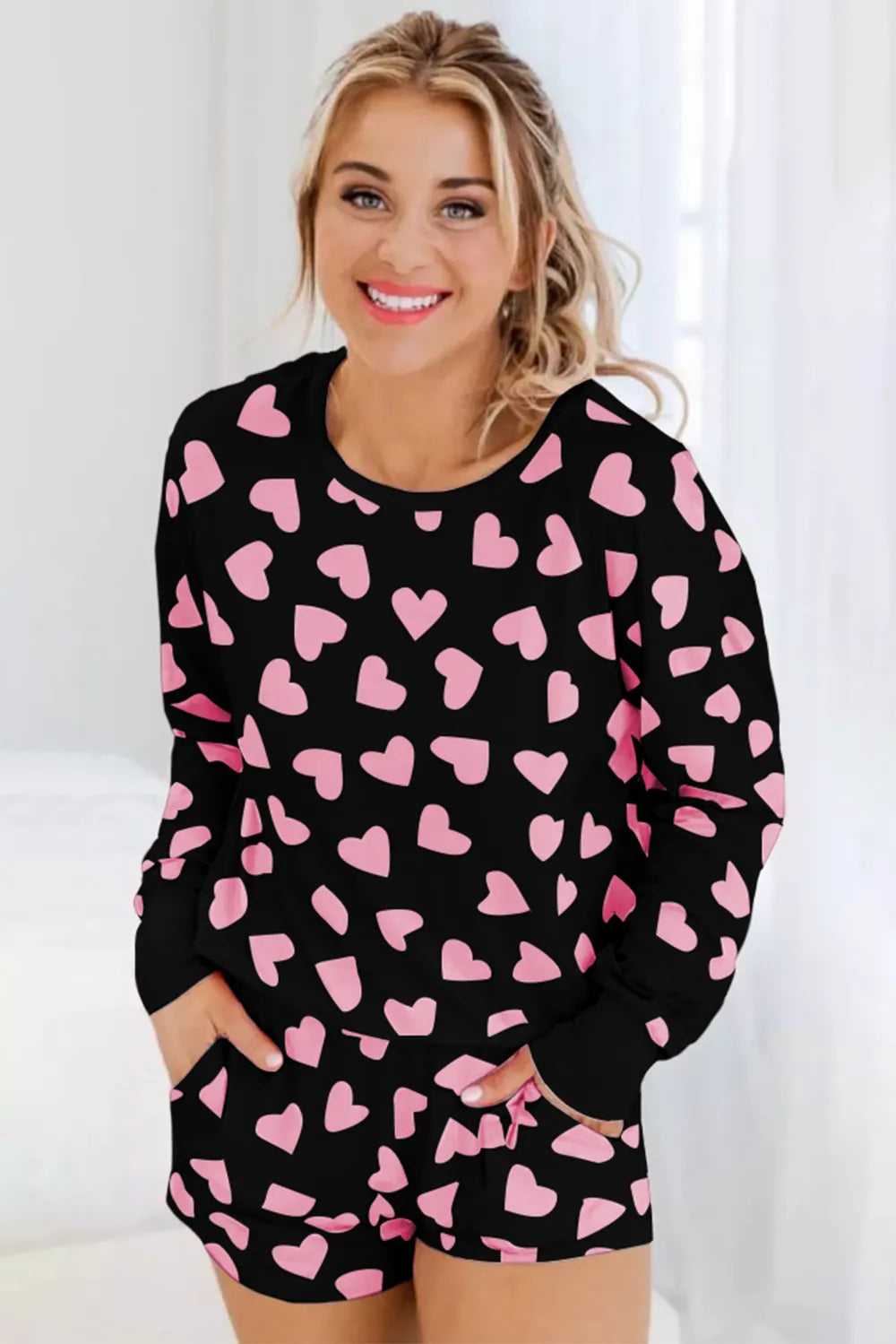 Black long sleeve top and shorts lounge set with pink heart print and ribbed cuffs.