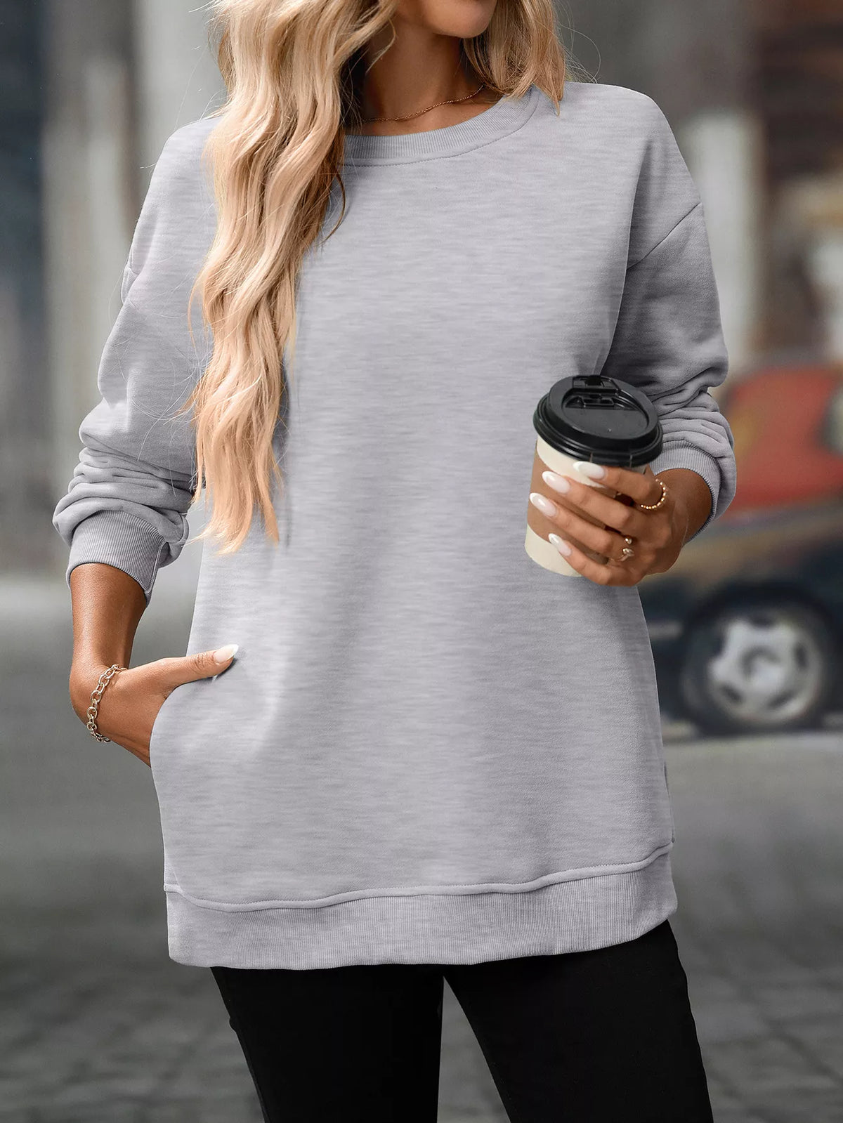 Light gray long sleeve casual sweatshirt with ribbed cuffs and hem, worn with black pants.