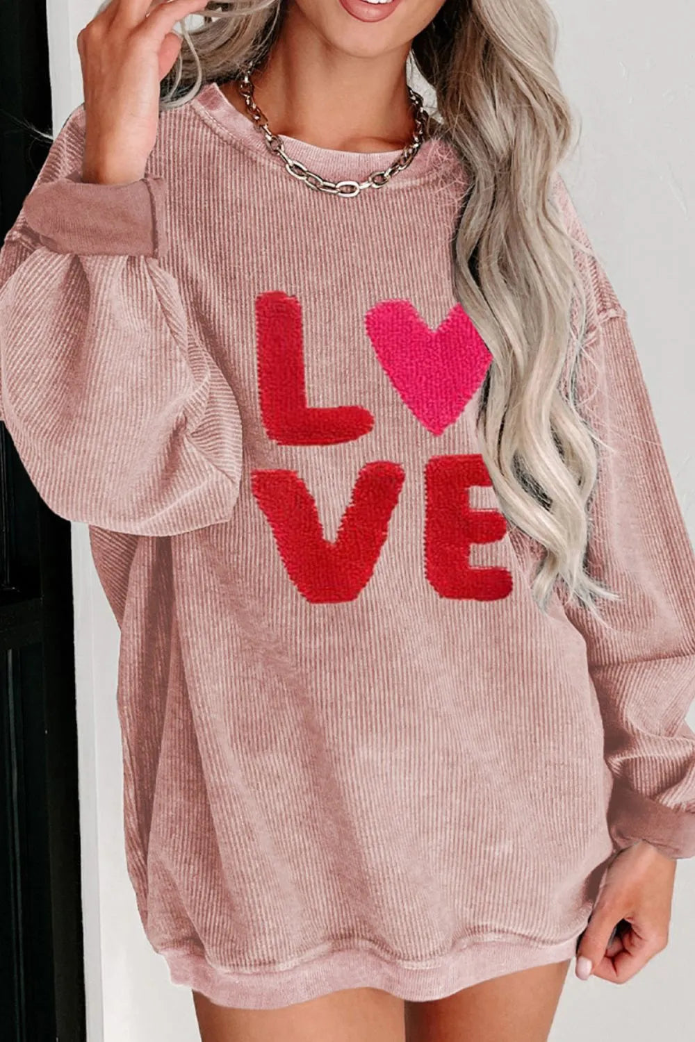 Dusty pink long sleeve sweatshirt with red LOVE lettering and heart-shaped O, relaxed fit.