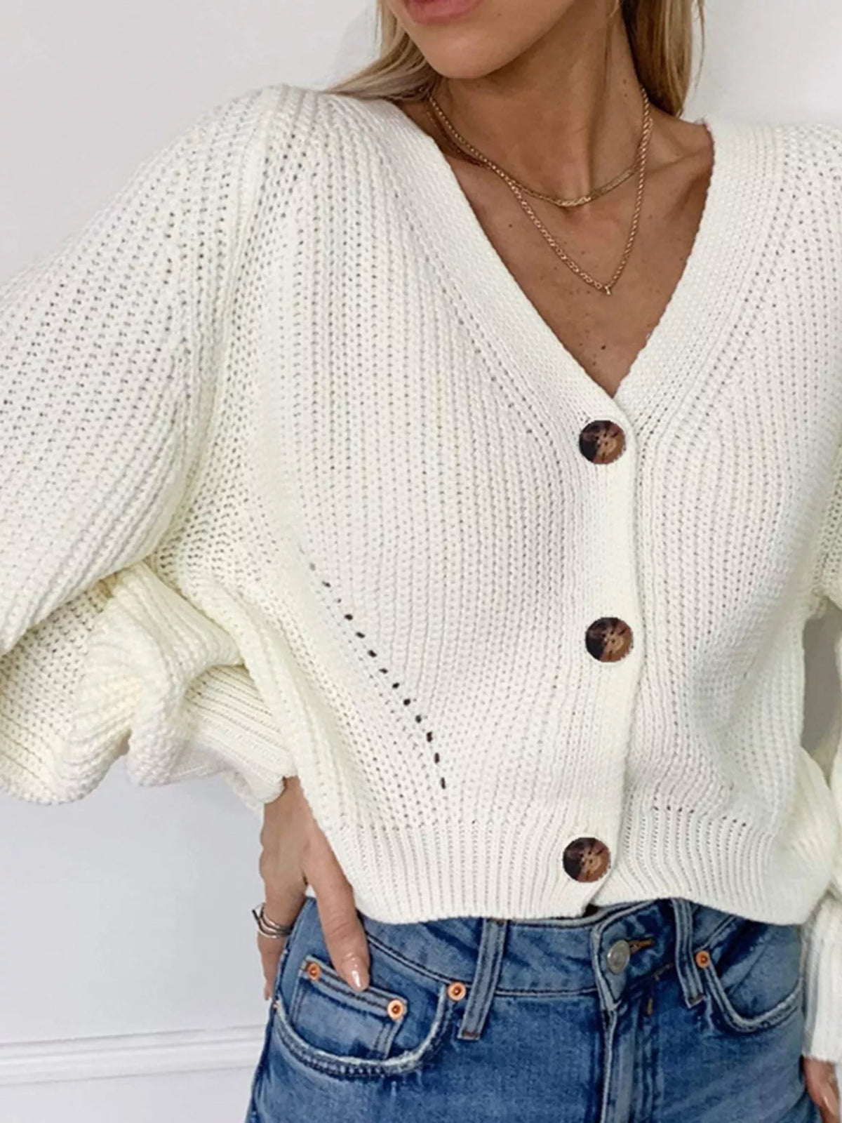 White chunky knit cardigan with oversized brown buttons and a deep V-neckline.