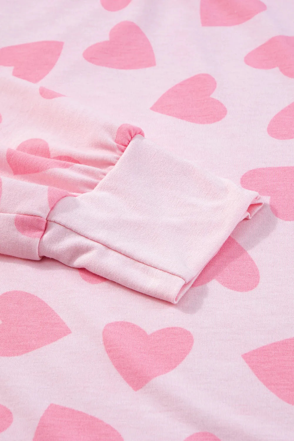 Blush pink long sleeve top with darker pink heart prints and fitted cuff detail.