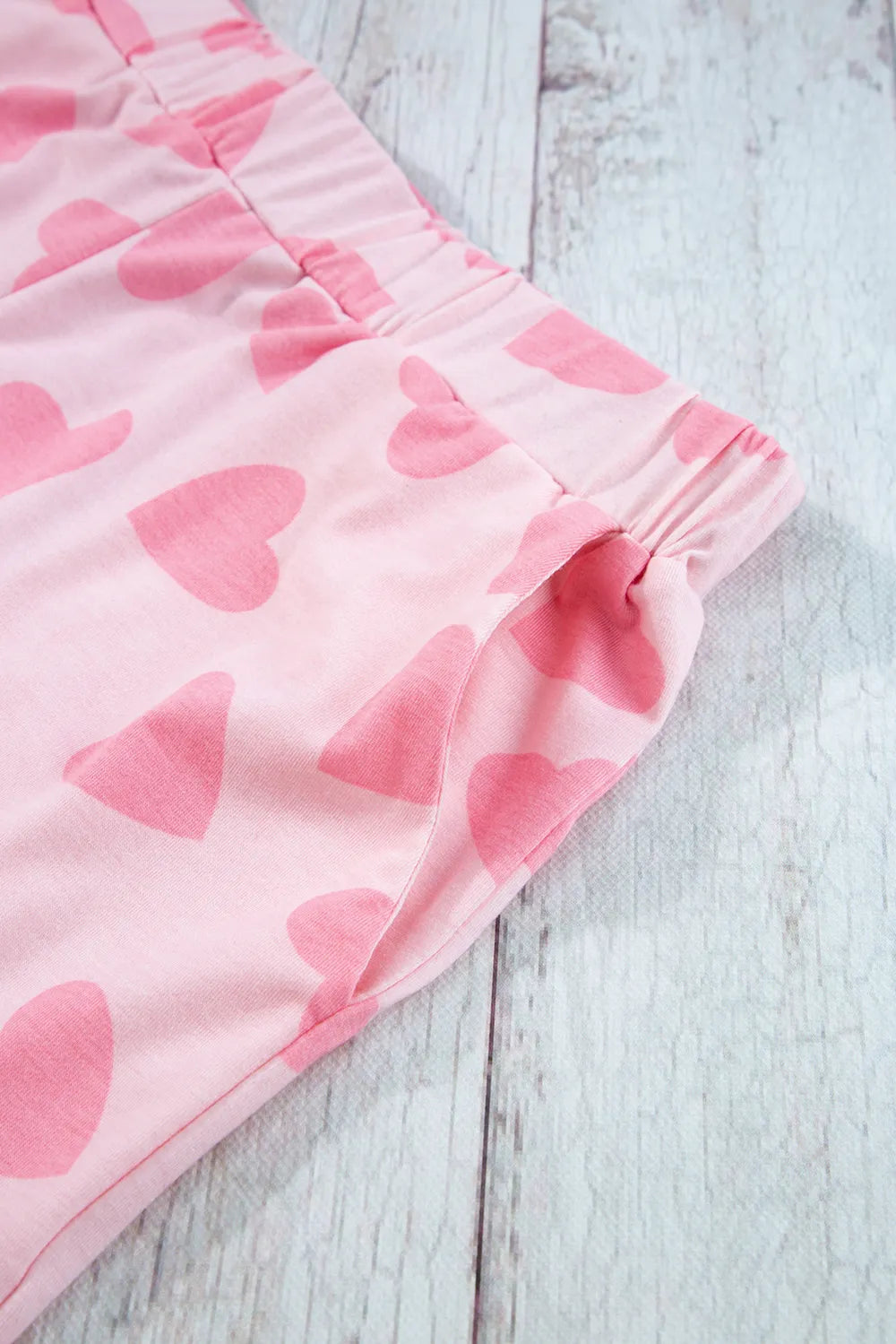 Blush pink lounge shorts with elastic waistband and darker pink heart print on soft fabric.