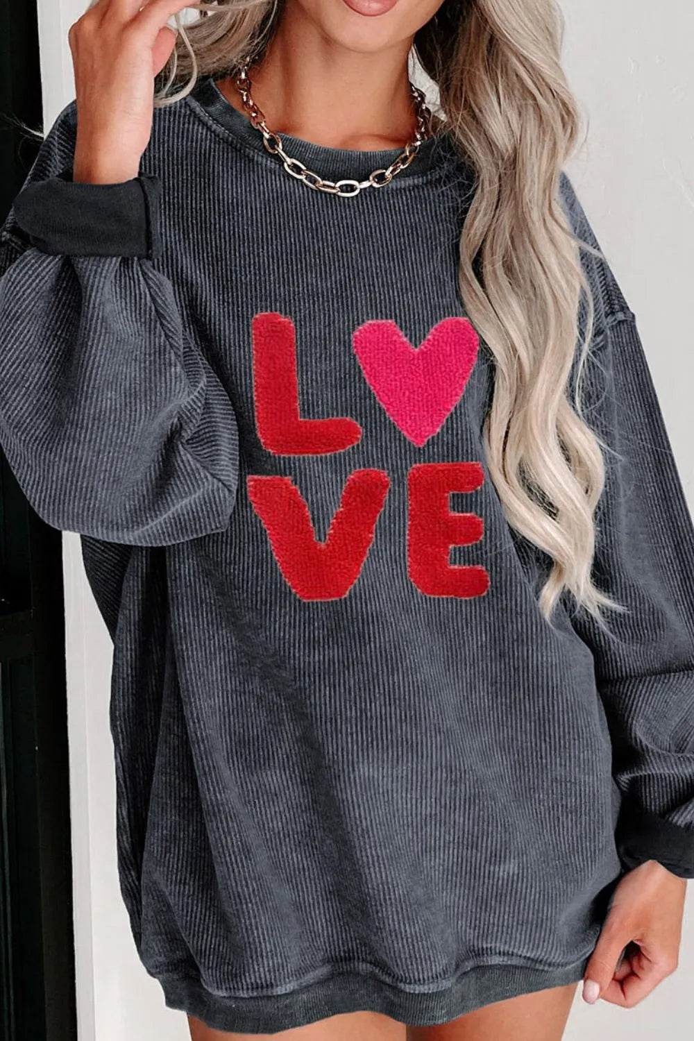 Dark gray sweatshirt with red "LOVE" letters and a heart replacing the "O," round neck, long sleeves.