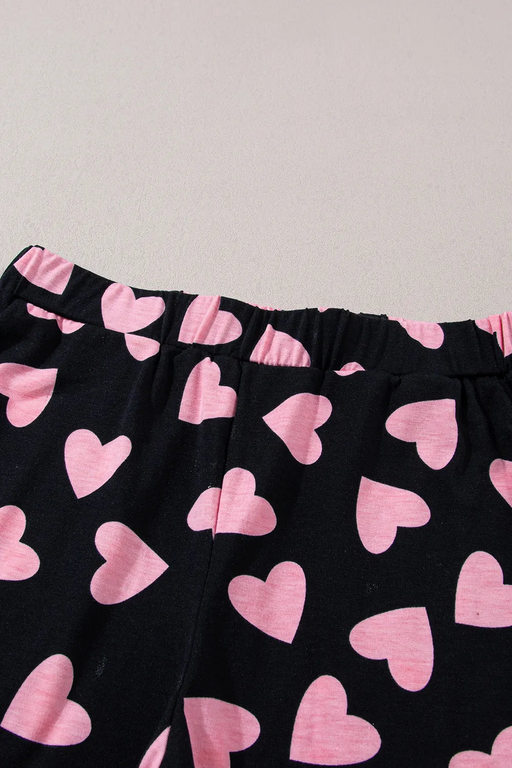 Black lounge shorts with pink heart prints and elastic waistband.