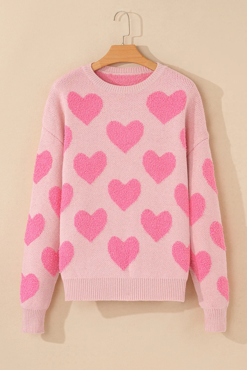 Blush pink sweater with bright pink heart jacquard pattern and round neckline.
