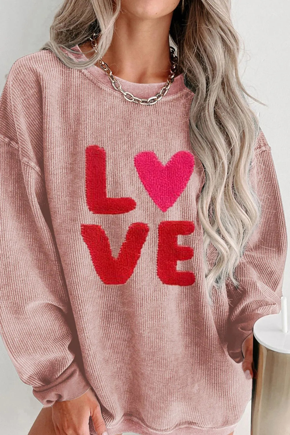Dusty pink long sleeve sweatshirt with red "LOVE" text and heart detail, relaxed fit.