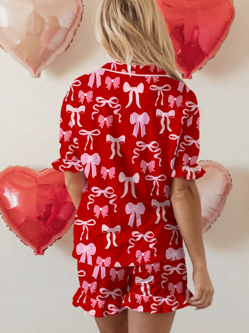 Red short sleeve pajama set with white bow prints and ruffled hem shorts, back view.