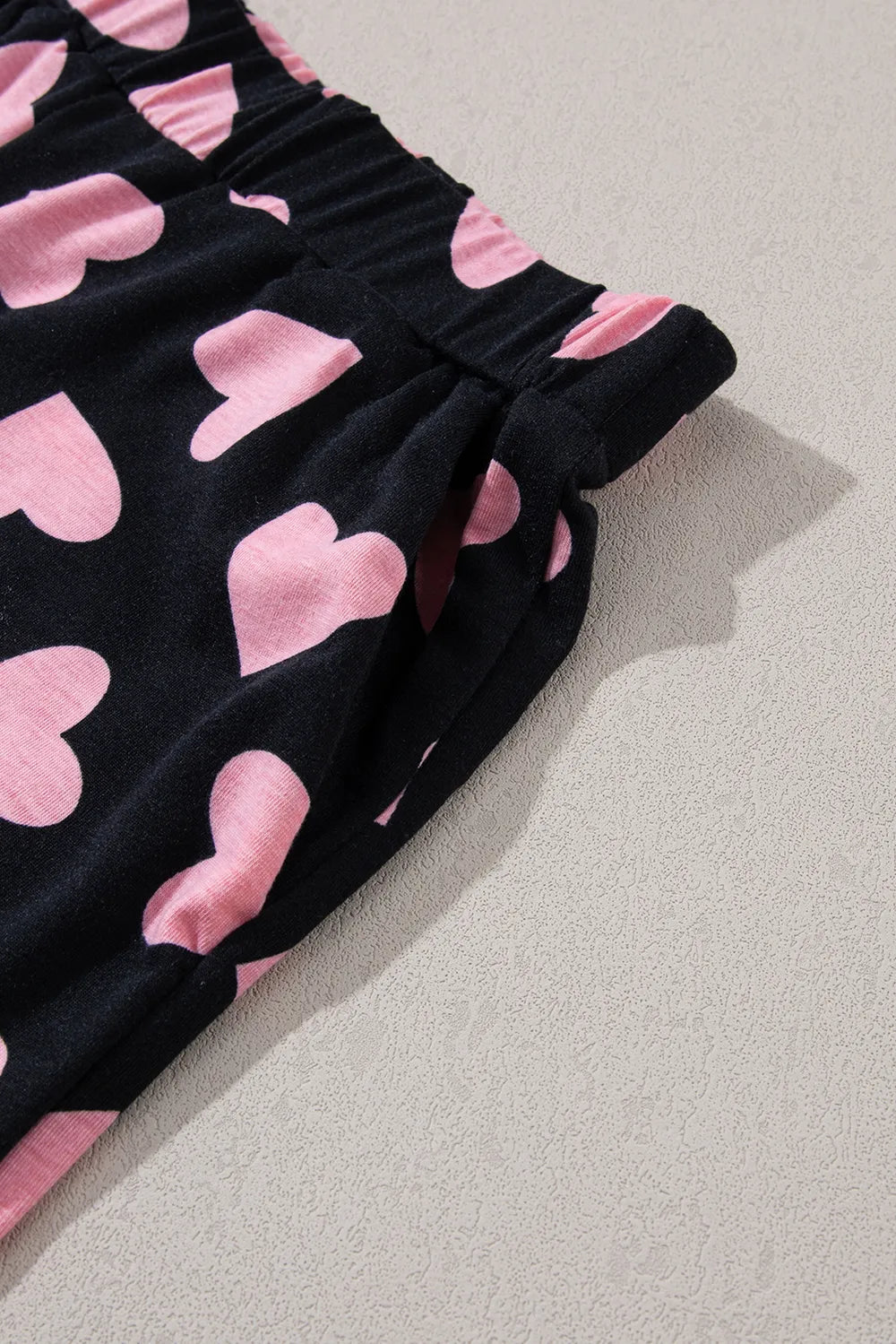 Black lounge shorts with pink heart prints and gathered elastic waistband.