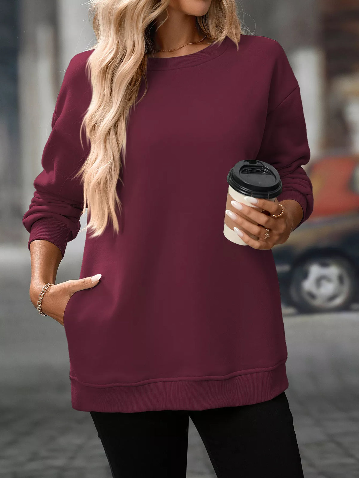 Burgundy long sleeve sweatshirt with crew neckline and side pockets, worn with black pants.
