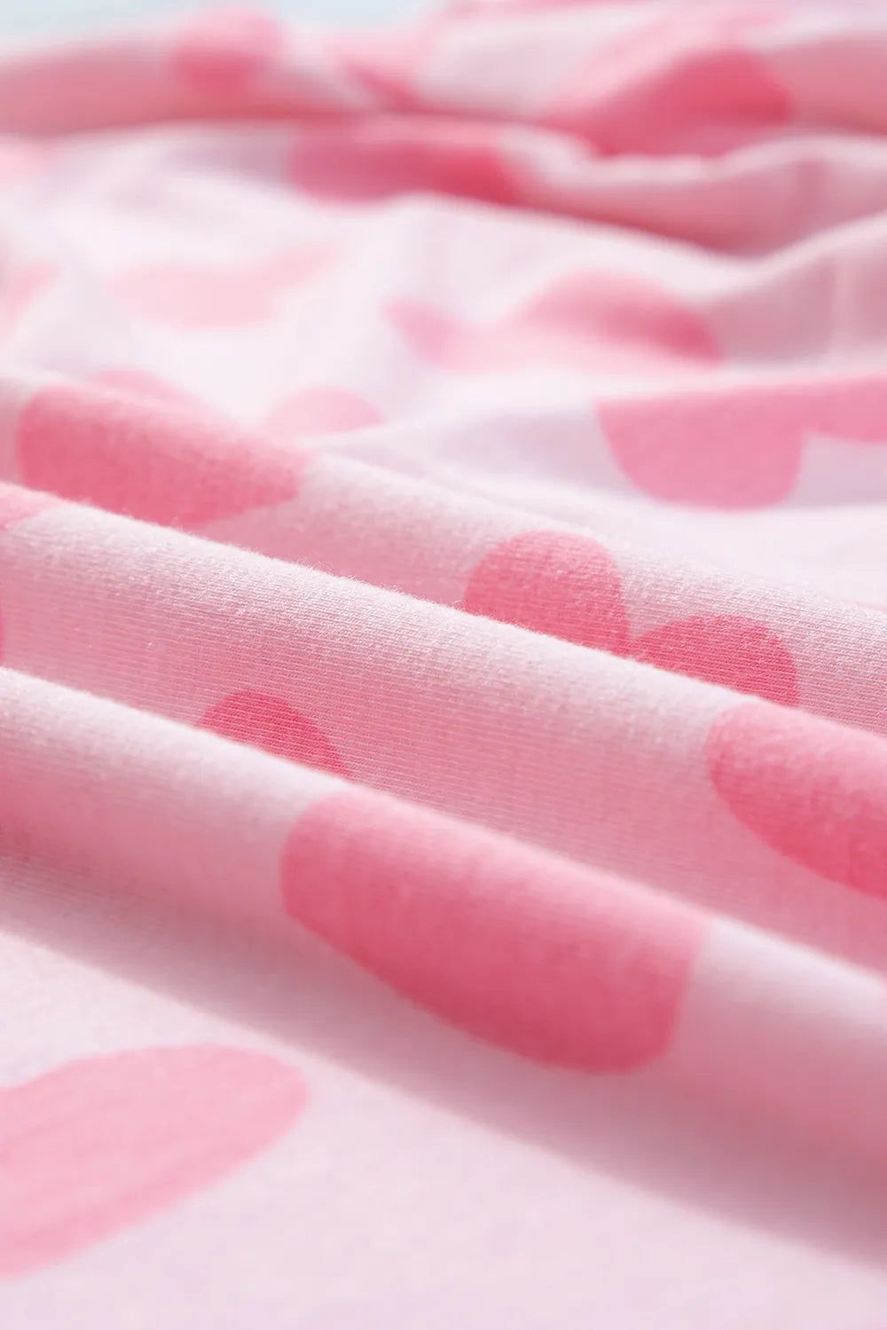 Soft blush pink fabric with large darker pink heart prints in a smooth, cozy texture.