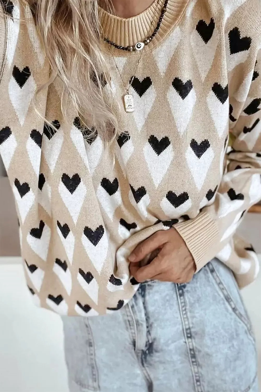 Khaki long sleeve sweater with black and white heart patterns, ribbed cuffs and neckline.