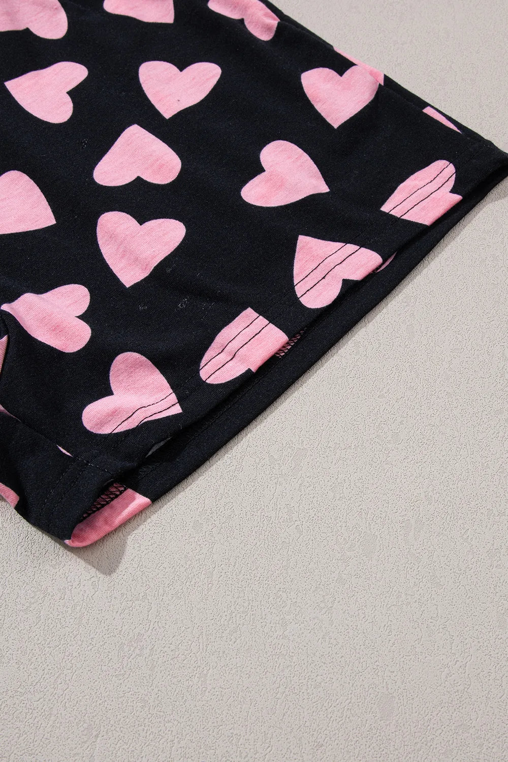 Black shorts with pink heart prints and scalloped hem detailing.