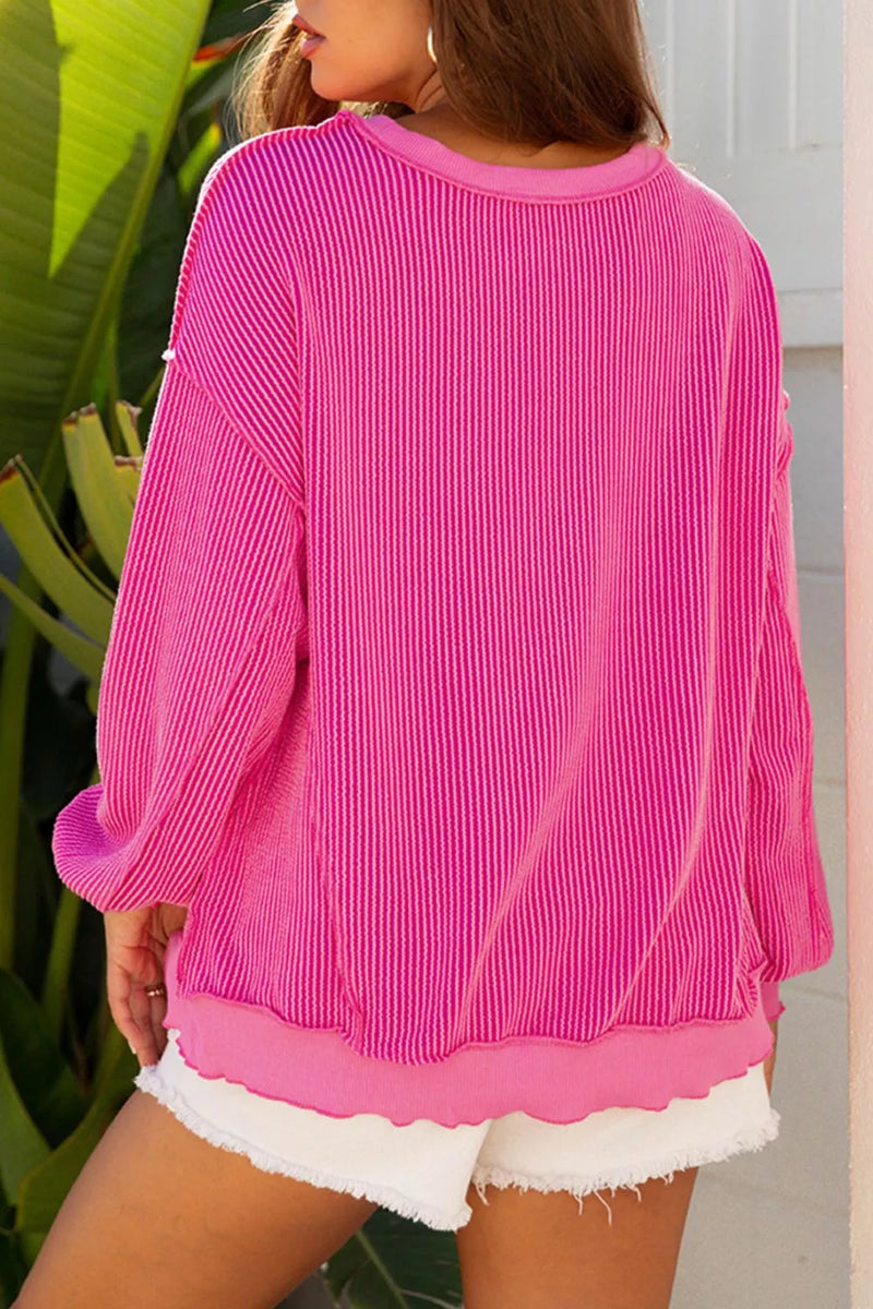 Hot pink twisted ribbed long sleeve top with relaxed fit and cuffed hem.