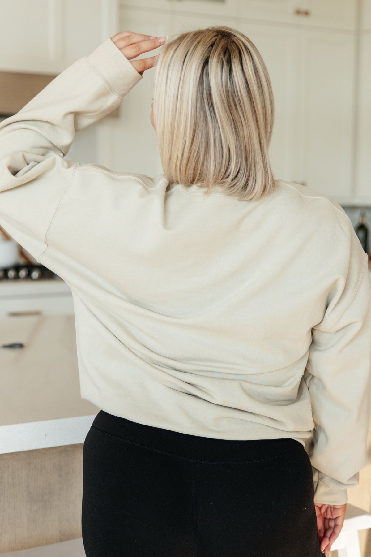 Beige pullover sweatshirt with long sleeves and relaxed fit on a model from the back.