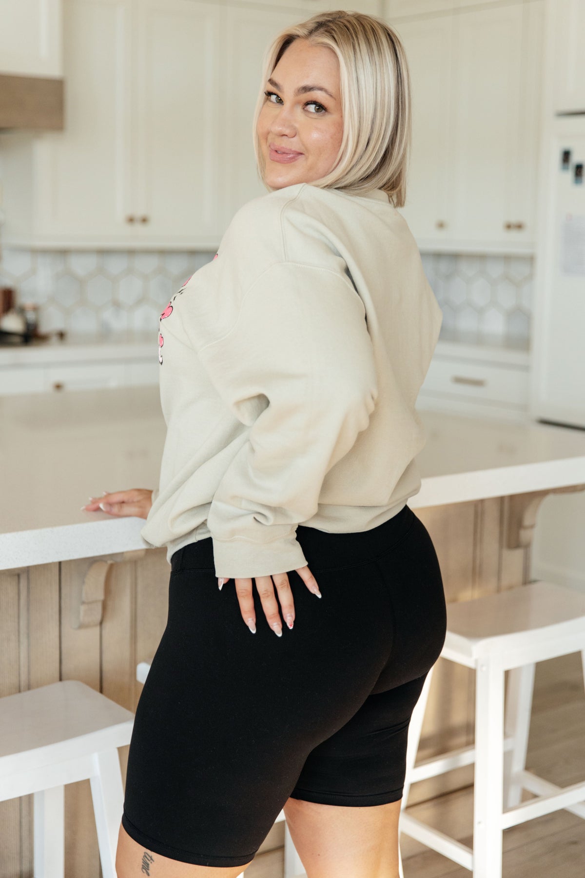 Beige pullover with "I'm A Sucker For You Valentine" in pink text on front, worn with black biker shorts.