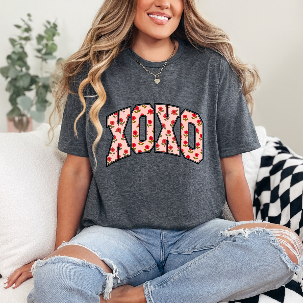 Charcoal gray cropped tee with floral "XOXO" graphic and short sleeves worn with ripped light-wash jeans.