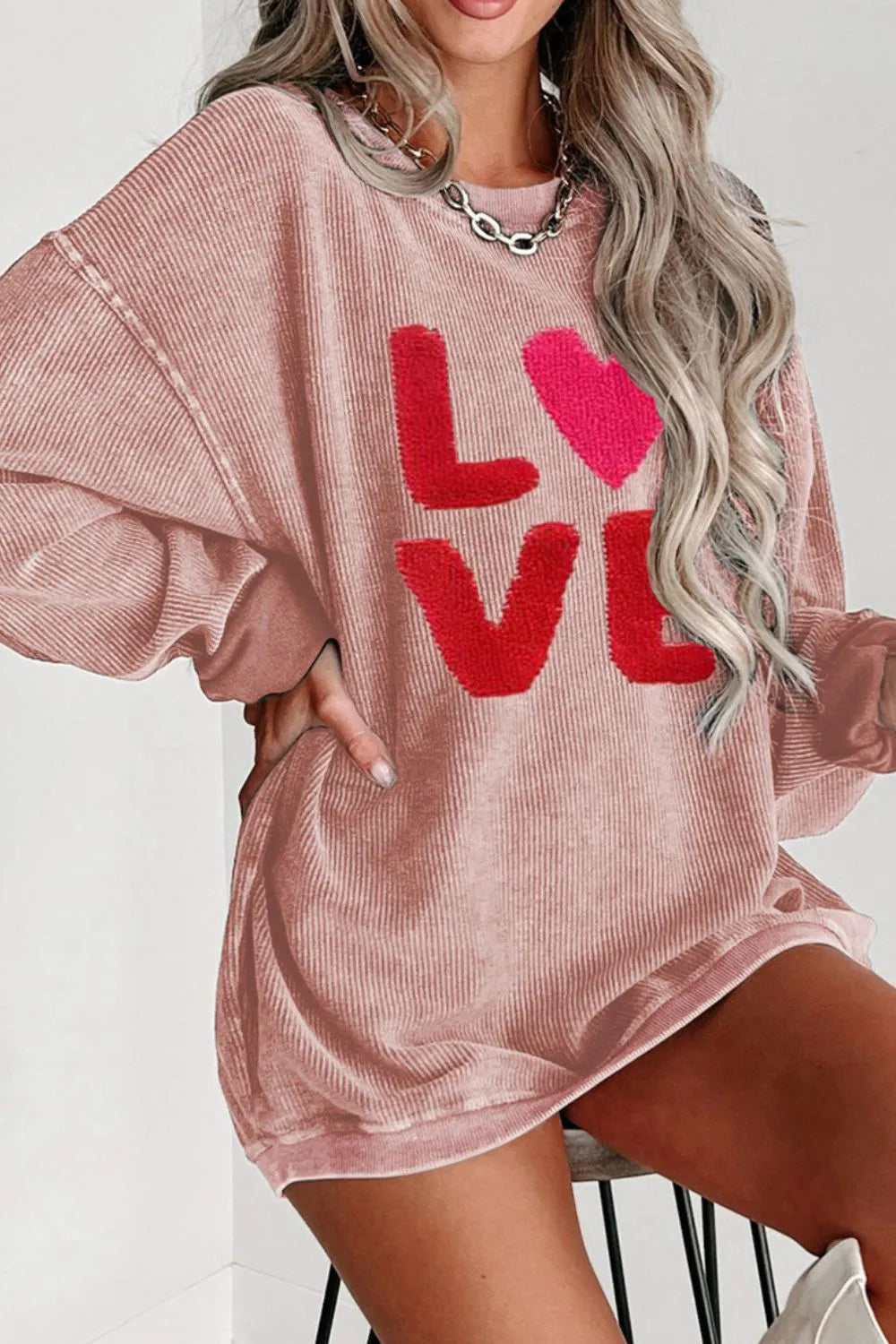 Dusty pink oversized sweatshirt with red LOVE text and heart graphic, long sleeves, round neck.