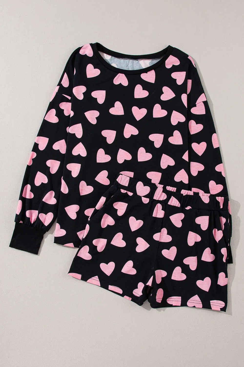 Black long sleeve top and shorts lounge set with large pink heart prints and ribbed cuffs.