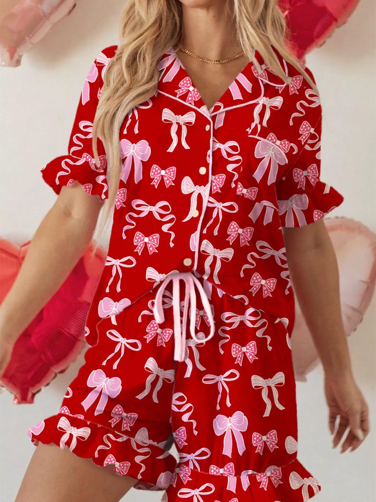 Red pajama set with white bow print, ruffled short sleeves, and drawstring shorts.