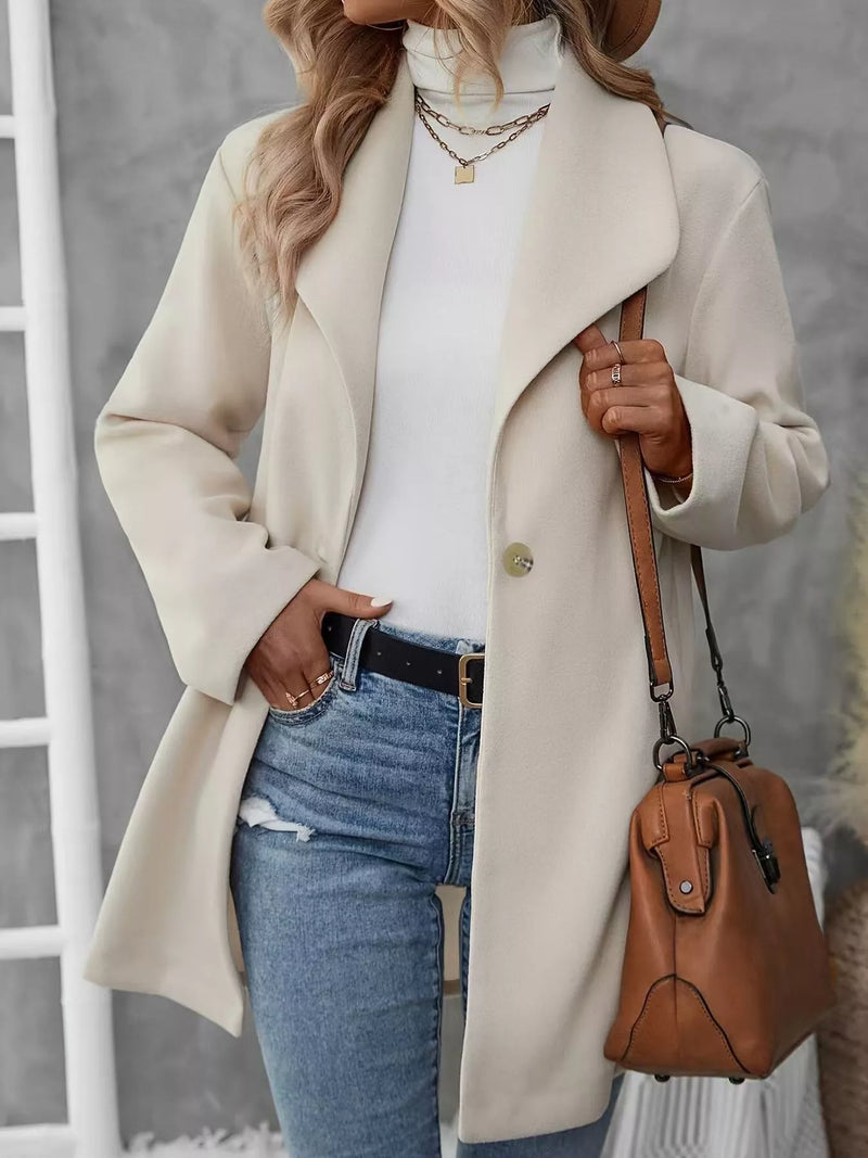 Apricot wool blend overcoat with lapel collar and single-button closure worn with white top and blue jeans.