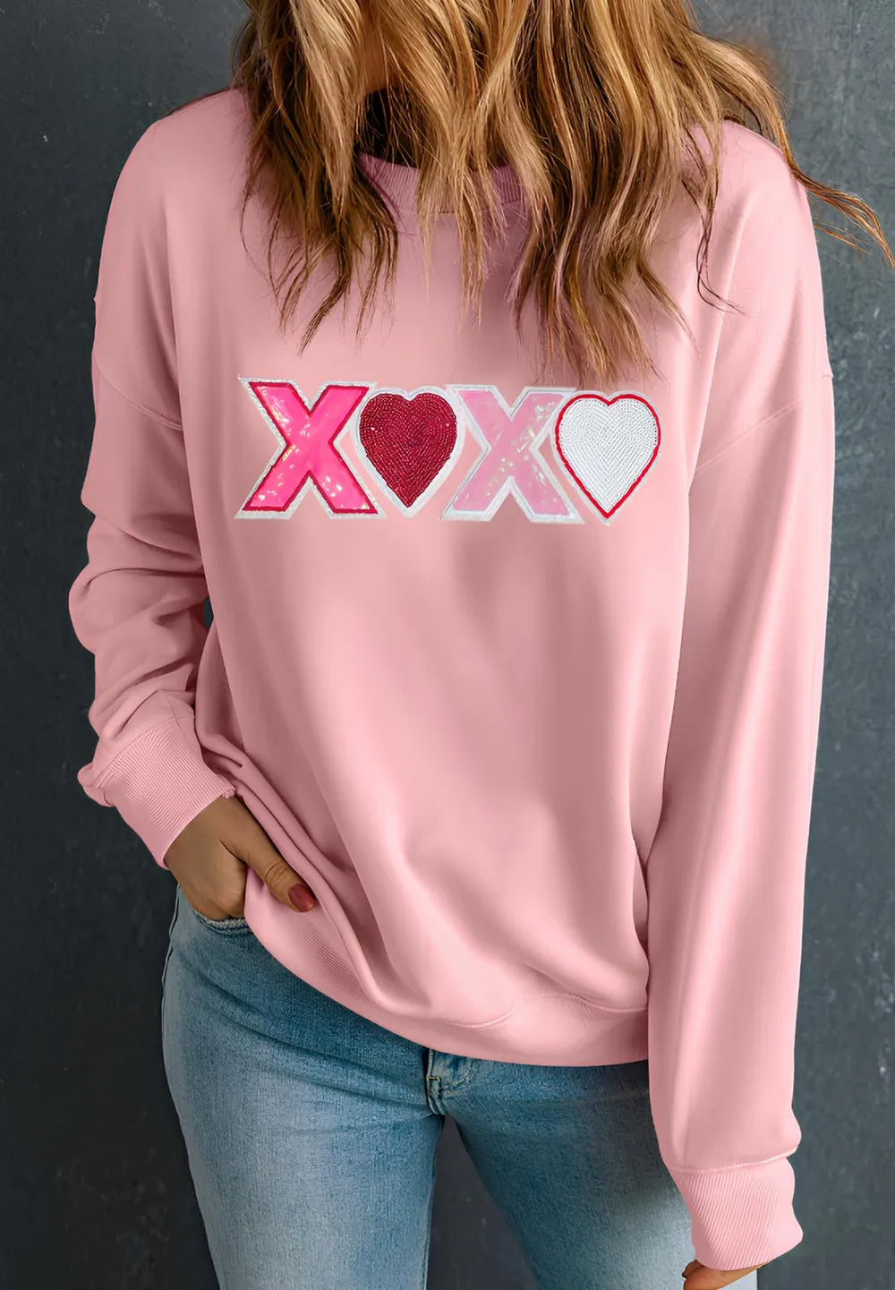 Dusty pink sweatshirt with XOXO and heart graphics in red, pink, and white on the front.