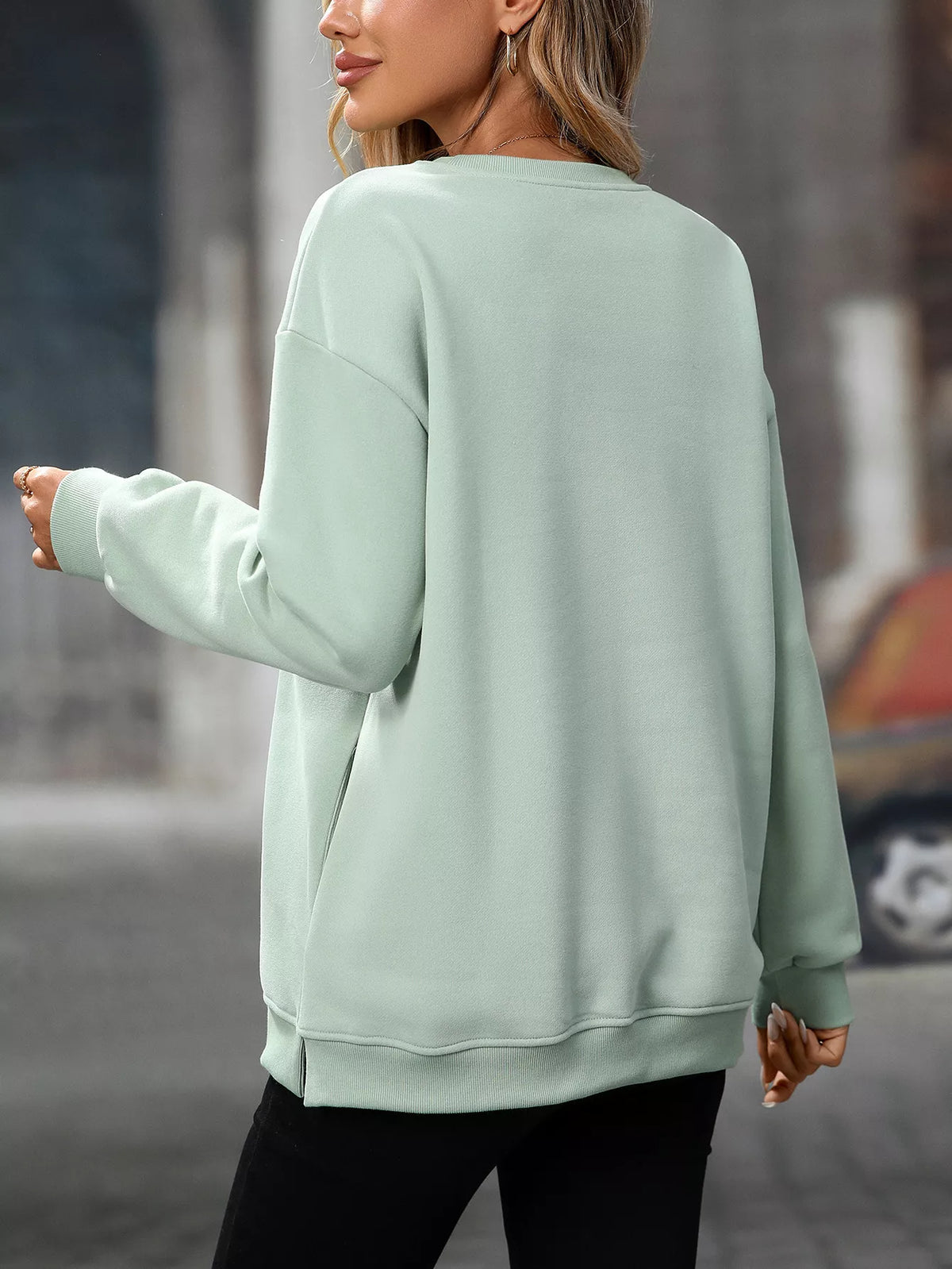 Light green casual long sleeve sweatshirt with relaxed fit and ribbed cuffs worn by a woman seen from back.