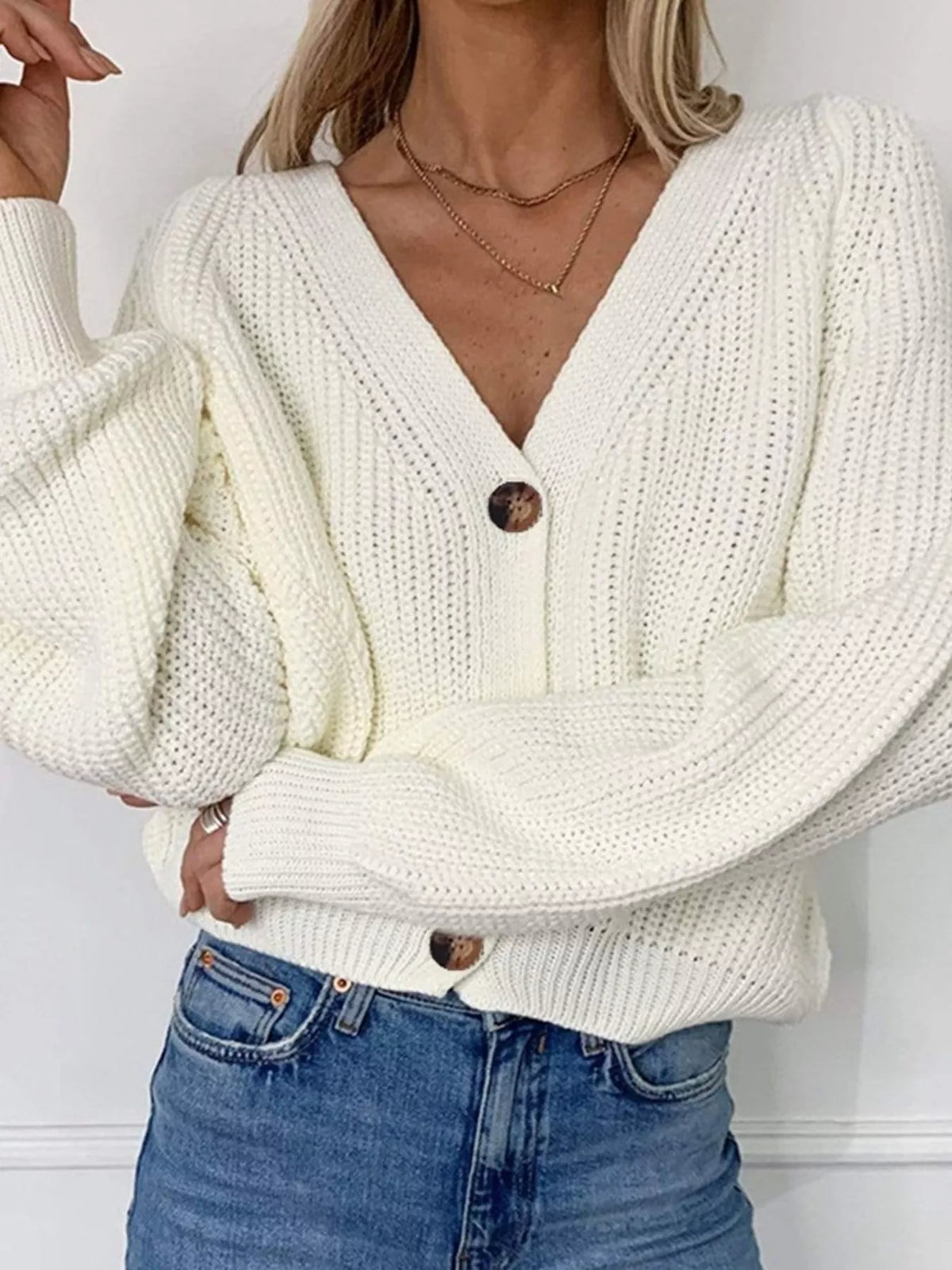 White chunky knit cardigan with large brown buttons and a deep V-neckline.