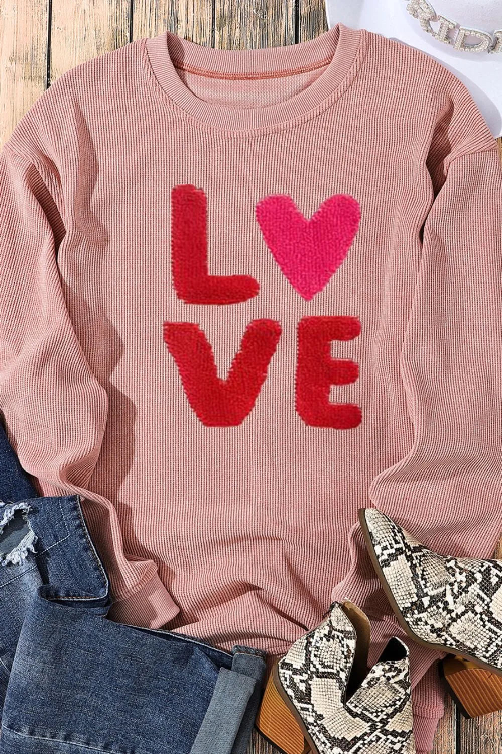 Dusty pink long sleeve sweatshirt with red and pink "LOVE" letters and heart-shaped "O" on front.