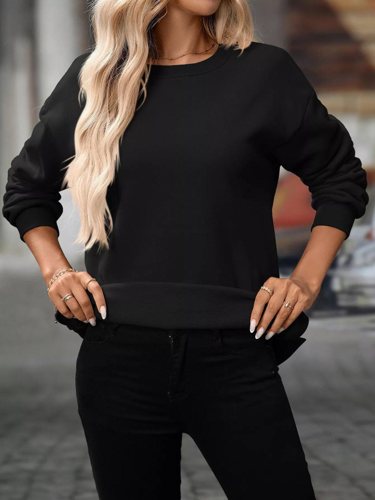 Black casual long sleeve sweatshirt with crewneck and ribbed cuffs, worn with black pants.