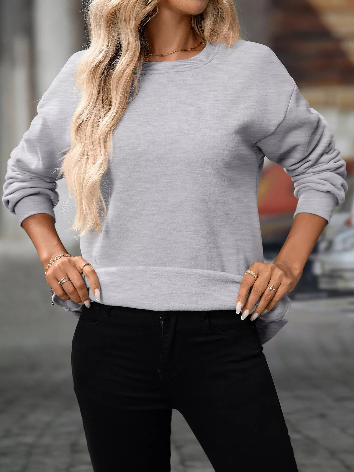 Light gray casual long sleeve sweatshirt with ribbed cuffs and hem, worn with black pants.
