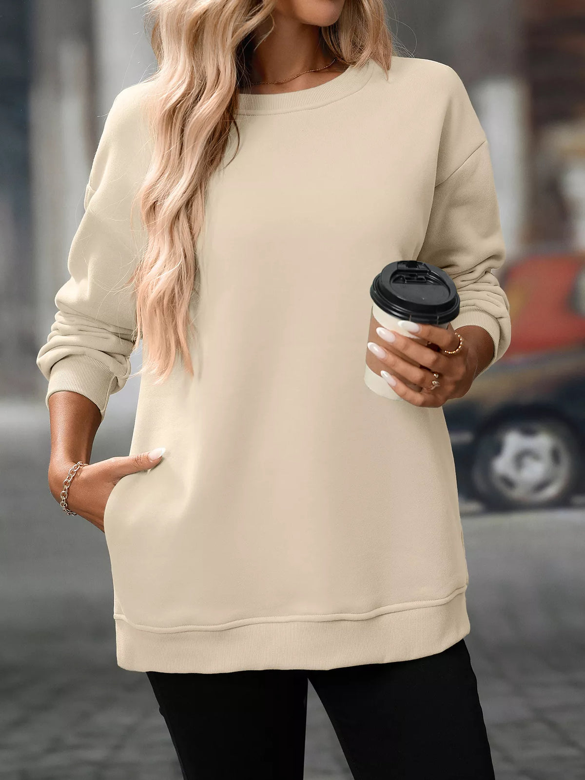 Beige long sleeve casual sweatshirt with crew neck and relaxed fit, worn with black pants.